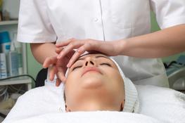 A woman getting her face cleaned by a person.